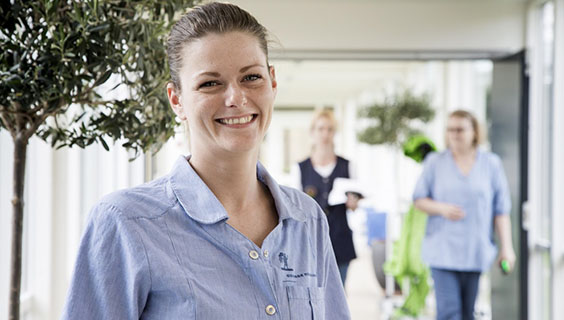 Sosu-assistent Trine Christel Pedersen står i en lys gang på det Plejecenter, hvor hun nu er ansat. 